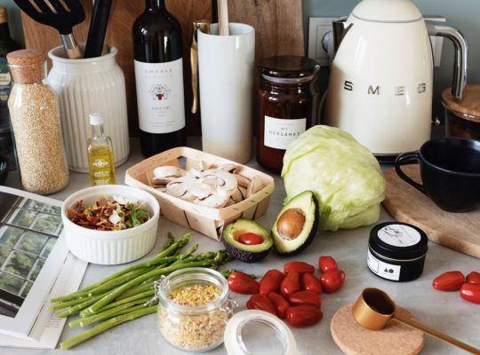 Assorted healthy food and vegetables set locating on gray countertop next to various utensils and appliances during cooking in stylish kitchen